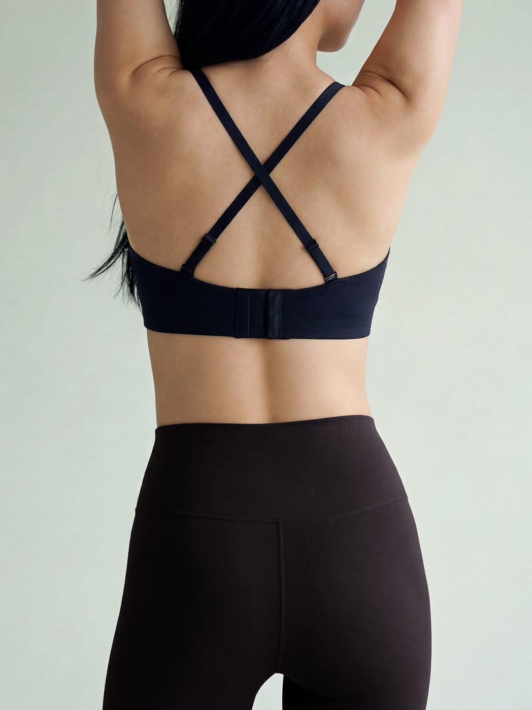 Person wearing a black sports bra and leggings on a light gray background