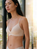 Woman wearing a beige bralette outdoors with blurred background