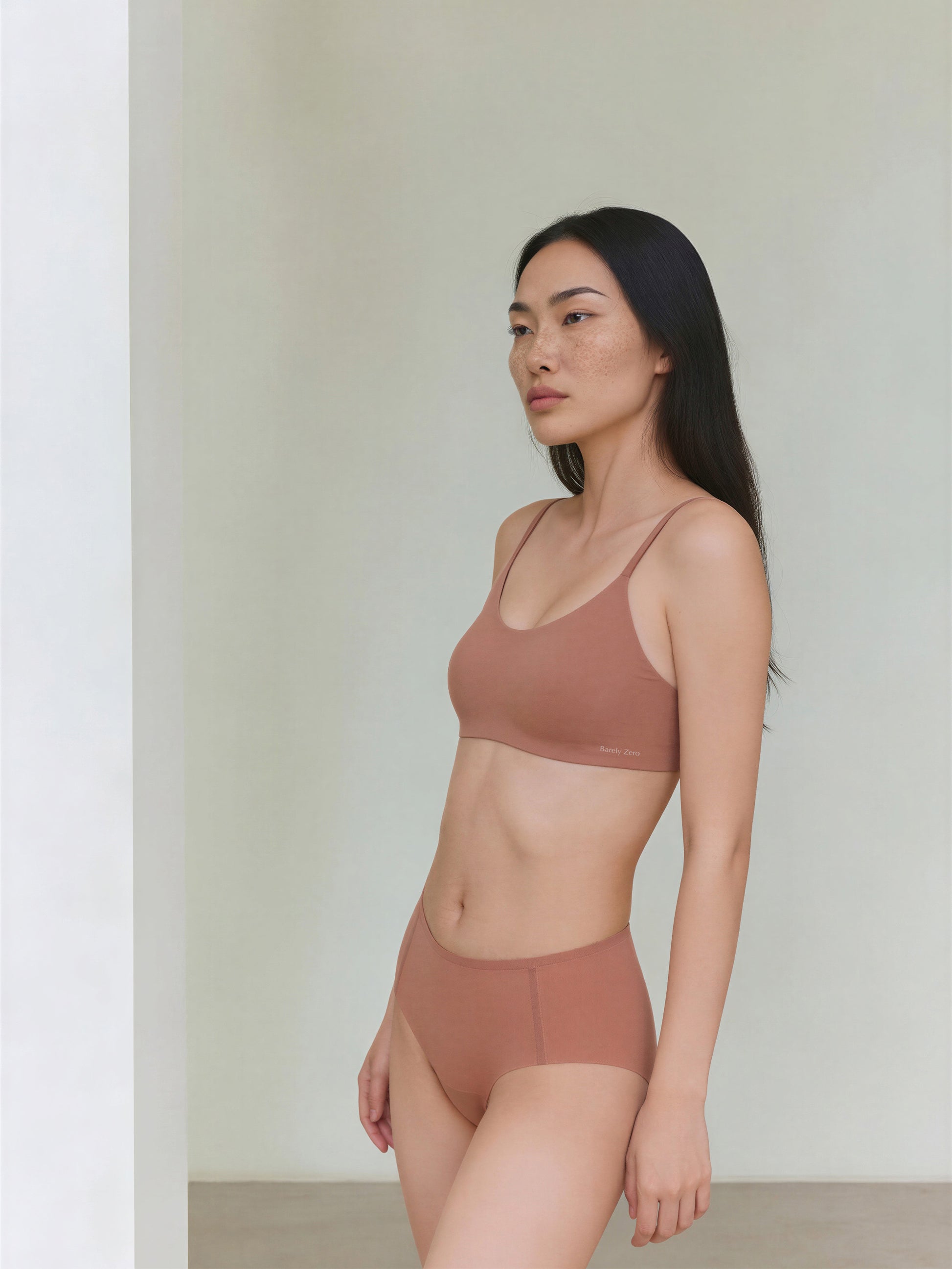 Woman wearing a brown bra and panties set against a plain background
