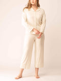 Woman wearing off-white button up pajama shirt and matching pajama bottom