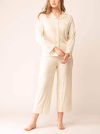 Woman wearing off-white button up pajama shirt and matching pajama bottom