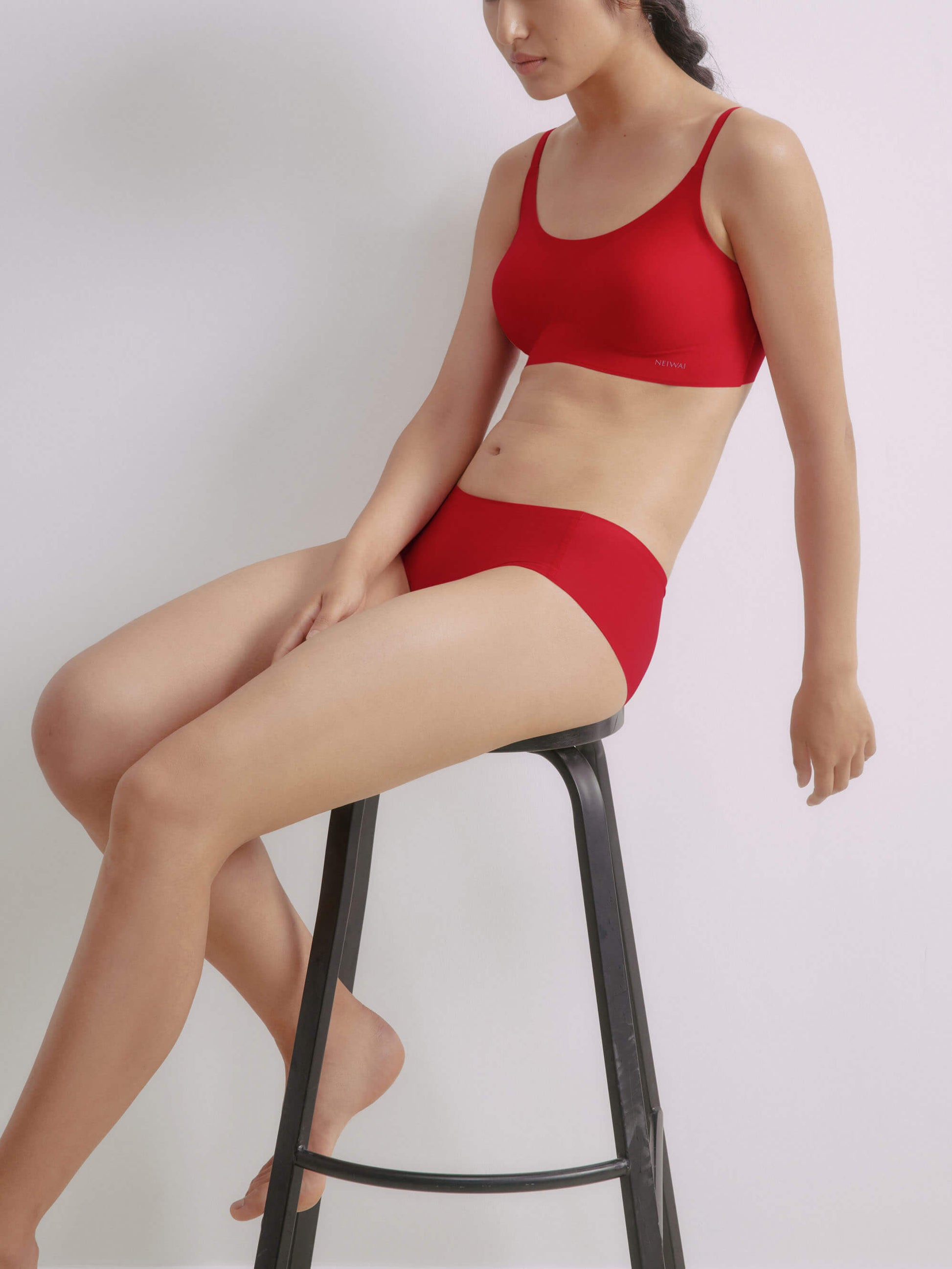 Woman sitting on stool and wearing matching red bra and briefs 