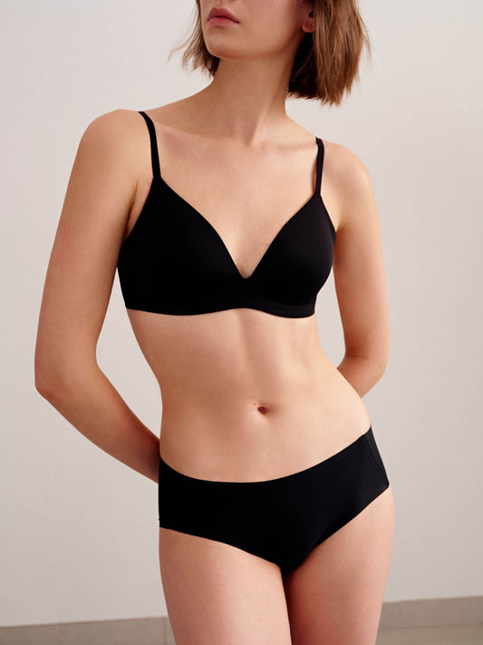 Full body view of model wearing matching black bra and brief set