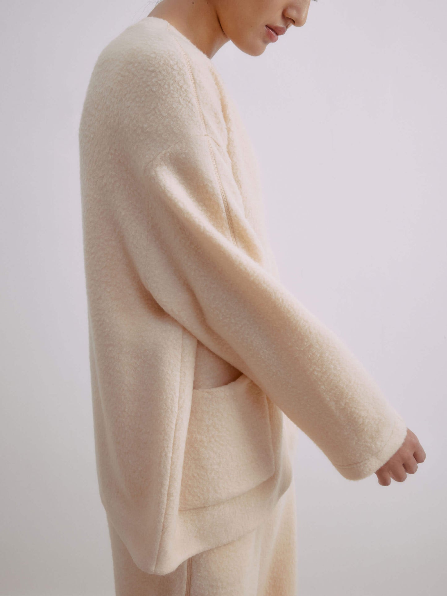 Side view of woman wearing cream colored wool fleece jacket