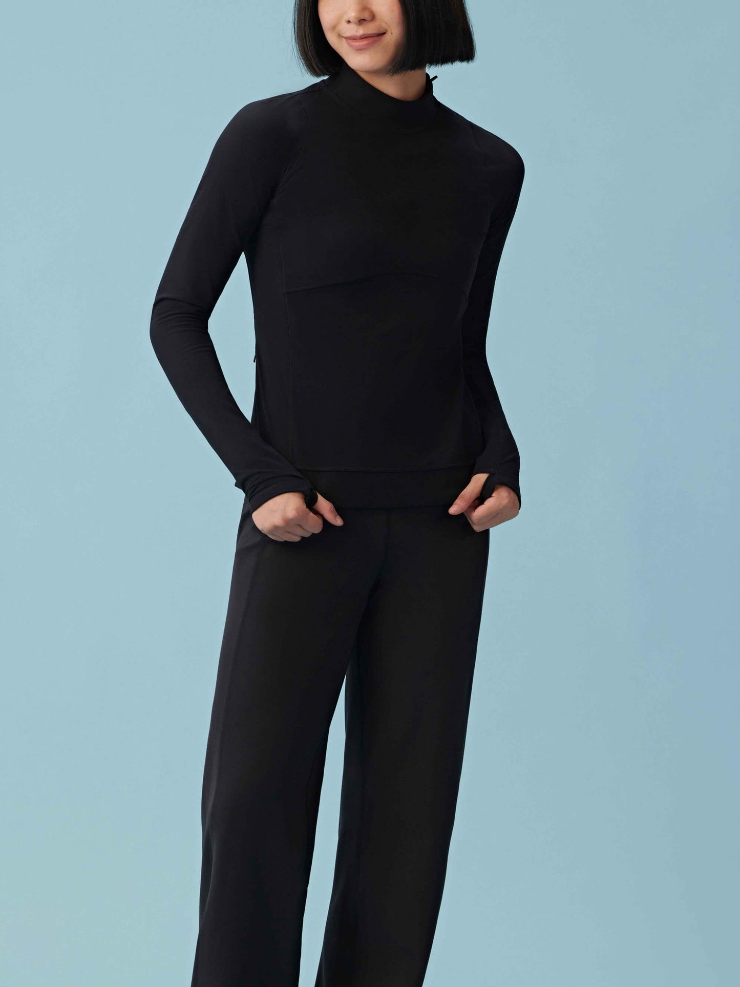 Front view of woman wearing black woven fleece pants