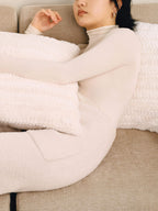 Woman laying down and wearing white wool seamless turtleneck