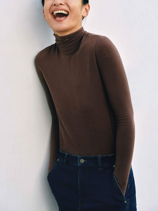 Woman smiling and wearing brown wool seamless turtleneck