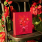 Red gift boxes with floral decoration on a chair surrounded by flowers