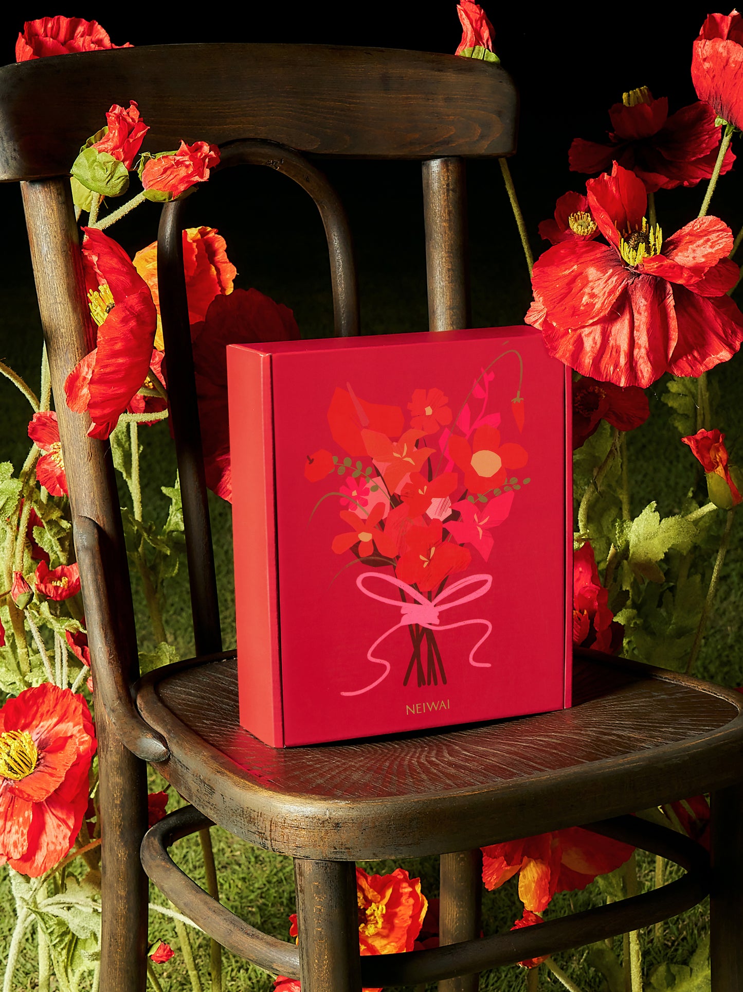 Red gift boxes with floral decoration on a chair surrounded by flowers