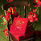 Red gift boxes with floral decoration on a chair surrounded by flowers