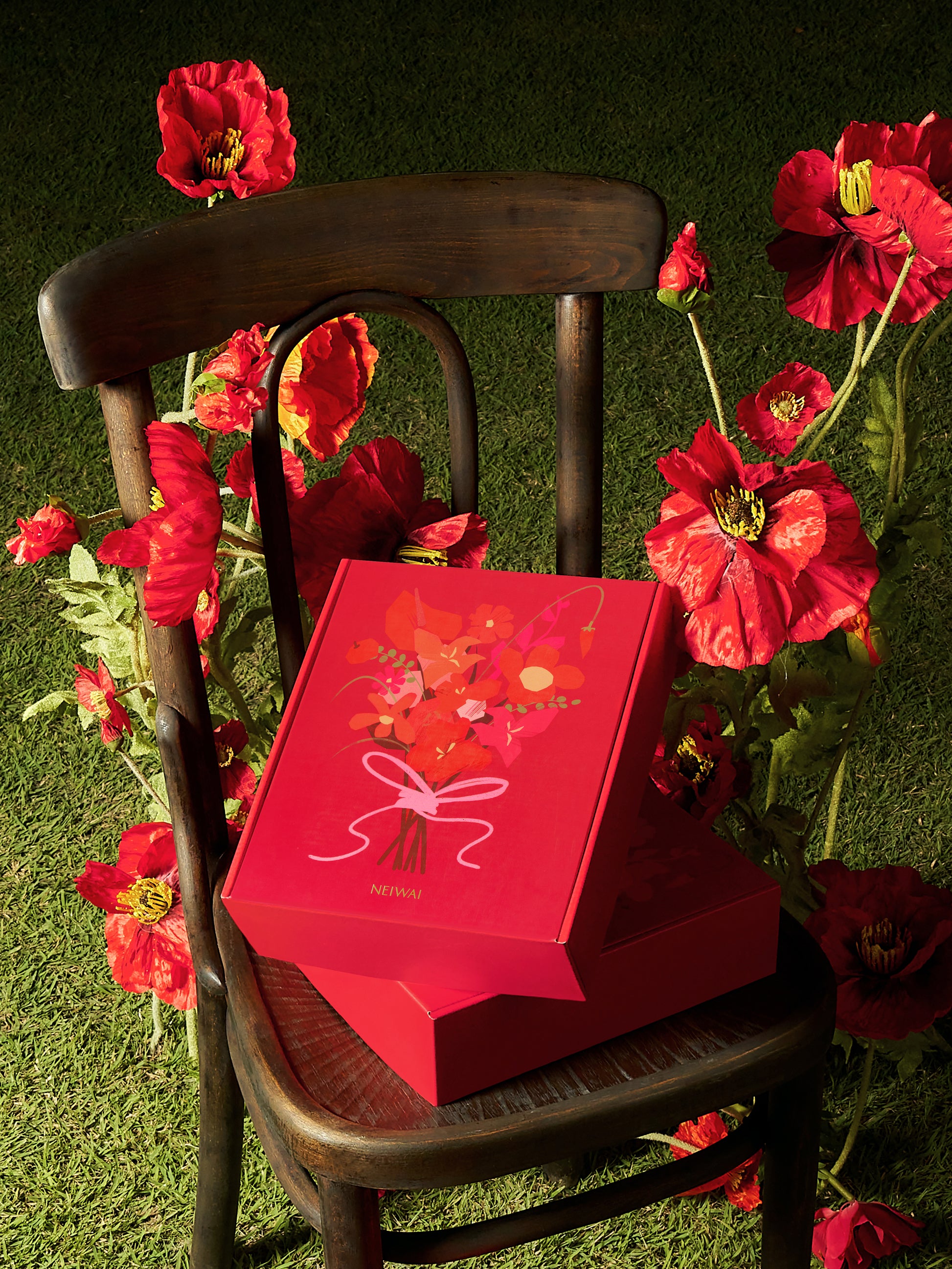 Red gift boxes with floral decoration on a chair surrounded by flowers