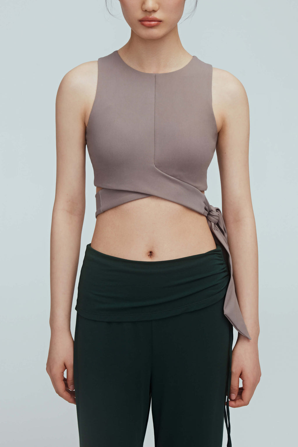a woman wearing a light brown wrap bra top and green leggings