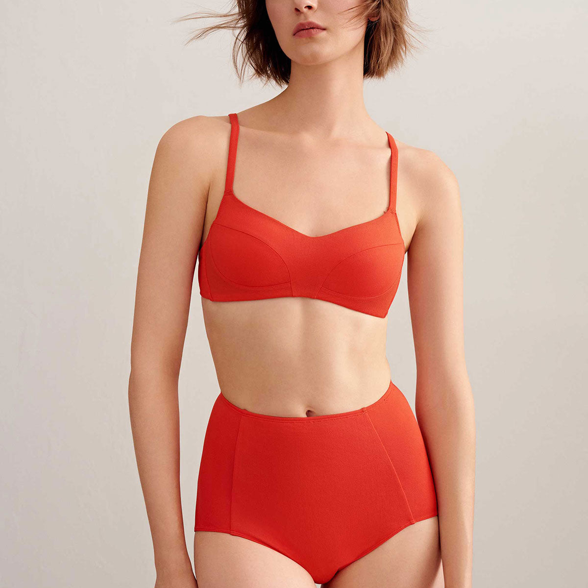 Woman wearing orange bikini top and high waisted bikini bottom