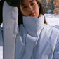 Woman wearing gray ski jacket holding a ski