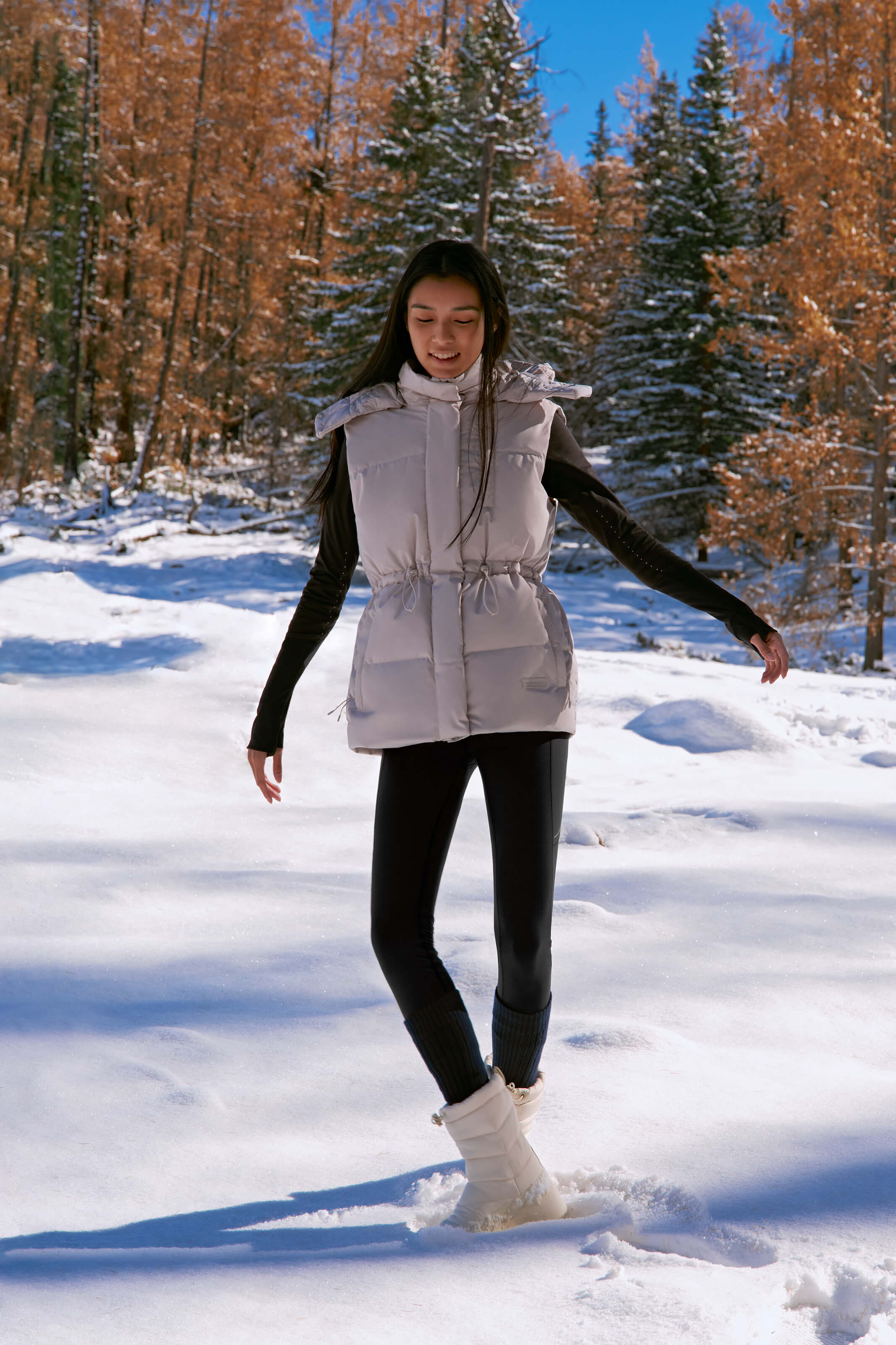 woman in grey down vest standing in the snow