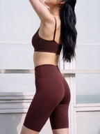 Person wearing a brown sports bra and shorts against a light background