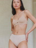 Woman wearing a beige bikini set against a neutral background