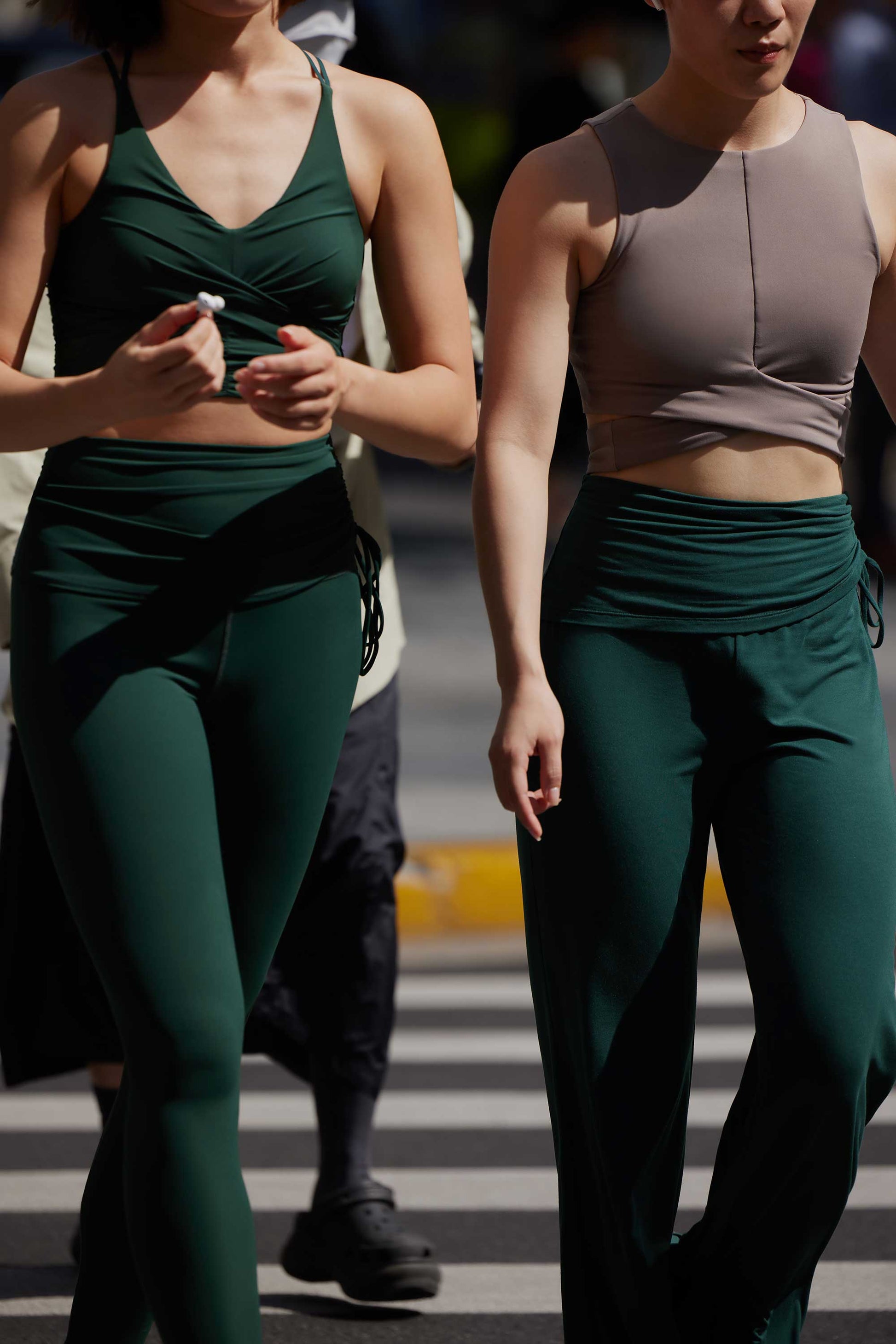 two women in the picture. the left woman wearing a green sports bra  and a green drawstring leggings. the right woman wearing taupe sports bra and green drawstring pants.