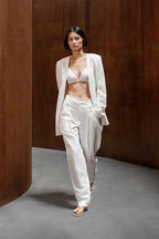 Front view of woman wearing ivory blazer, ivory bra, and ivory pants.