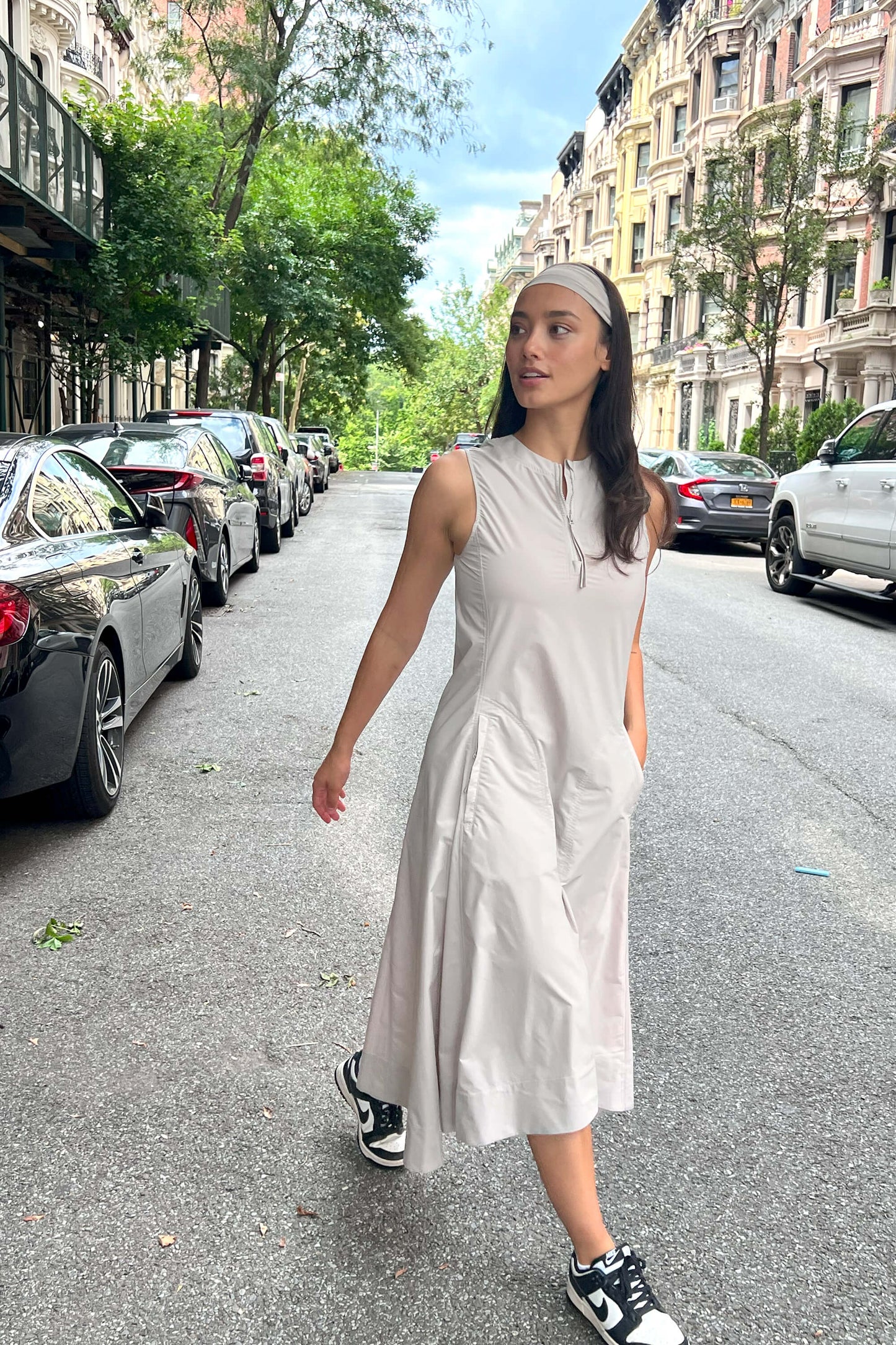 Woman wearing gray dress and headband walking on a street