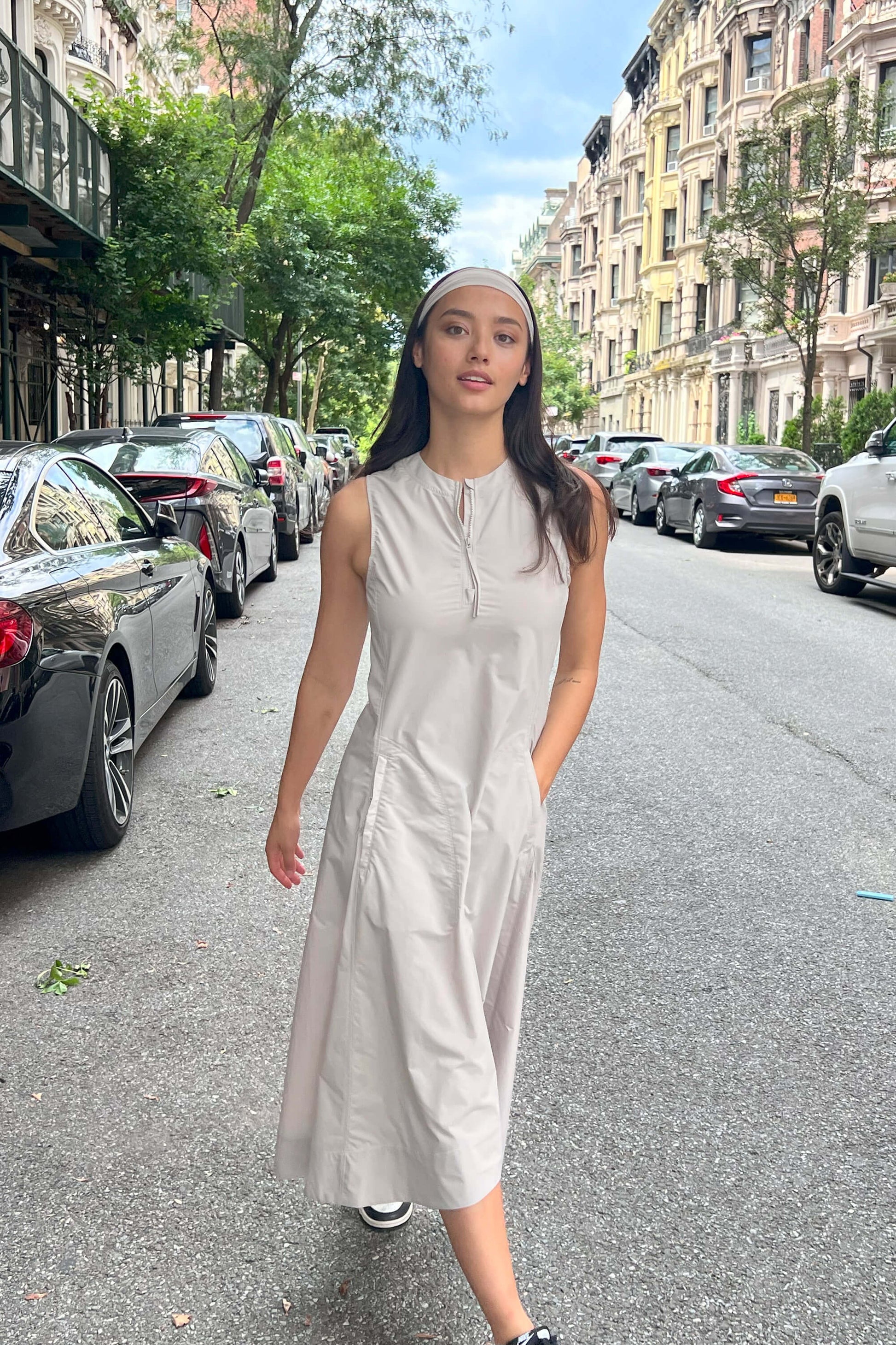 Woman wearing gray dress and headband walking in a street