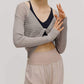 front view of a women wearing a neutral color woven jogger and a navy bra covered by a mauve color see thru knit top with a knot.