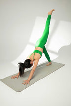 woman in green sports bra and leggings doing yoga
