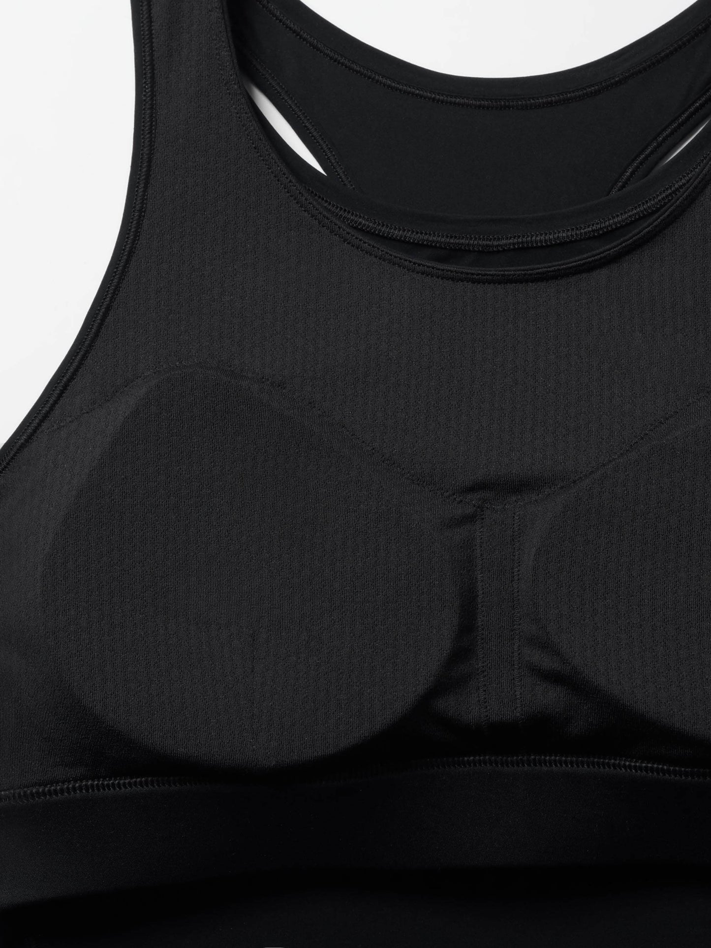 The image shows a close-up of the interior of a black racerback sports bra, highlighting its padded cups. 