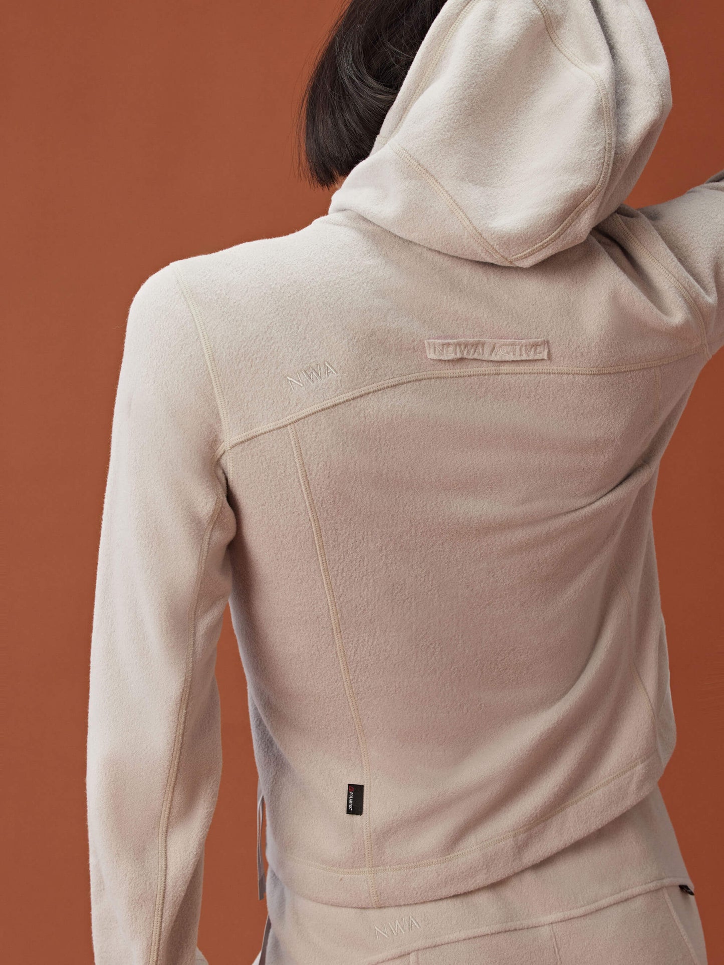 back of woman in beige zipped hooded fleece jacket