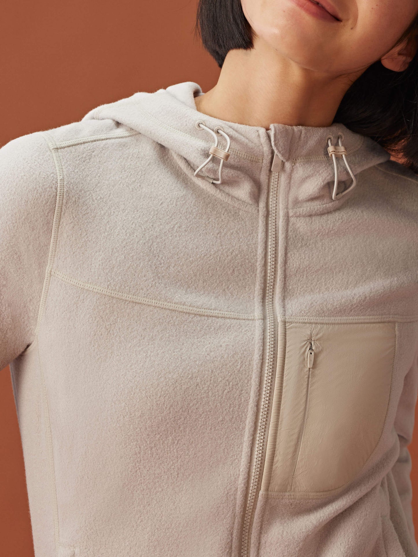 close up of woman in beige zipped hooded fleece jacket showcasing the collar