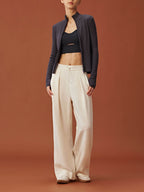 woman in dark purple zipped ribbed cardigan, black sports bra and white pants