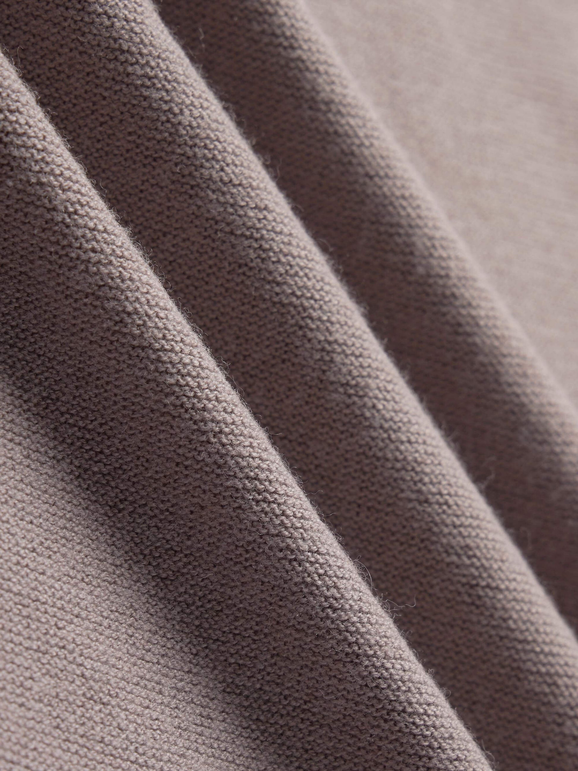 Close-up view of a taupe-colored knit fabric, showcasing its fine, textured weave and soft appearance.