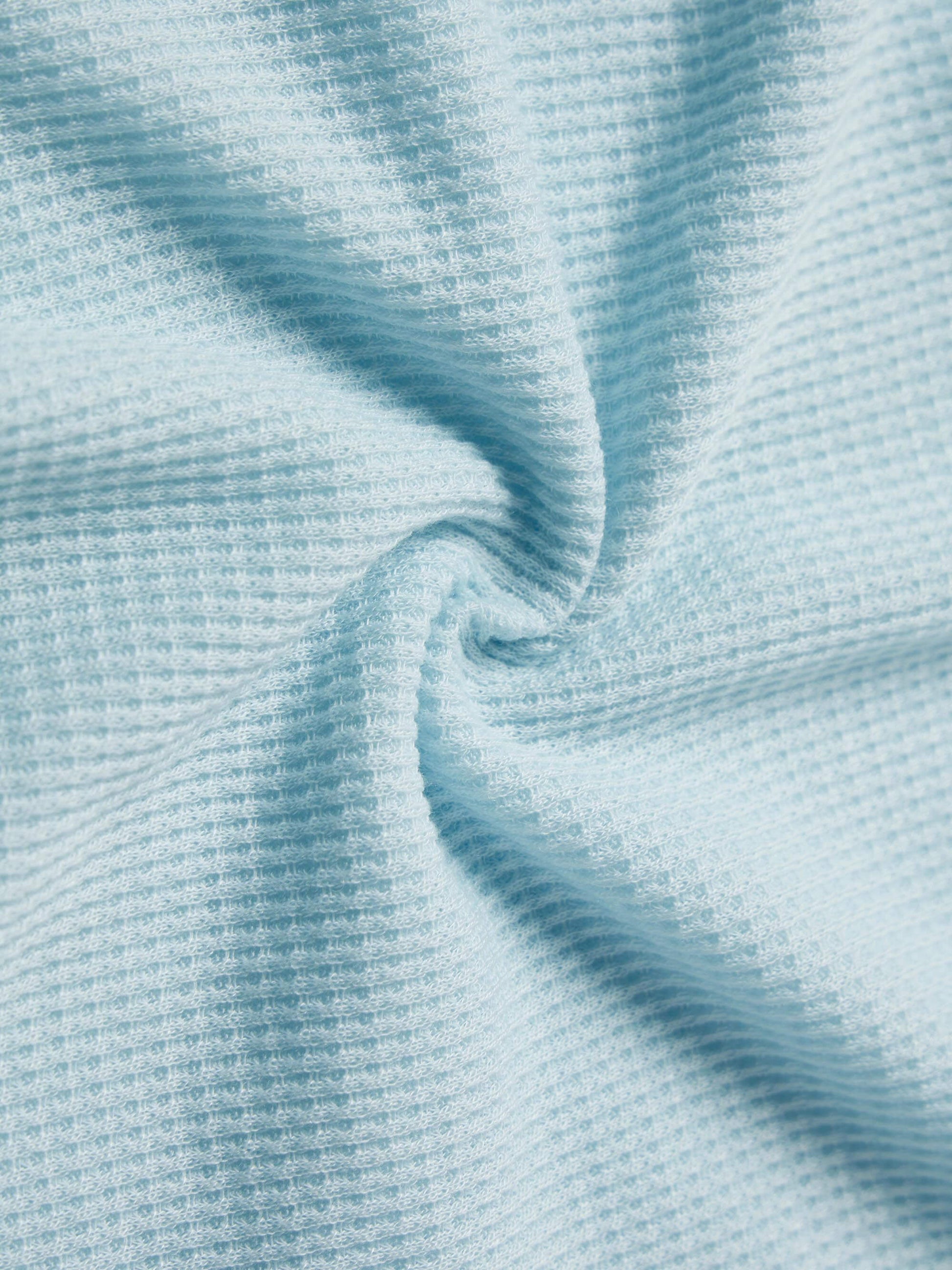  close-up view of light blue waffle-knit fabric, showcasing its textured grid pattern and soft, stretchy material.