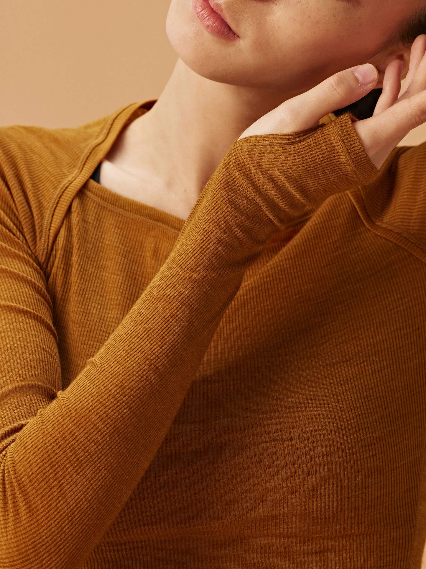 close up of woman in golden brown wool top showcasing the thumbhole.