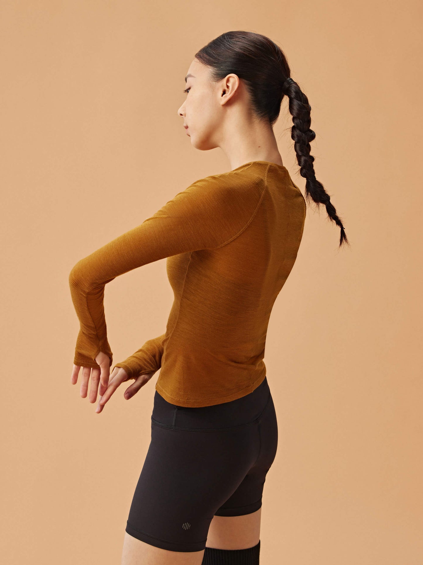 side of woman in golden brown wool top and black biker shorts