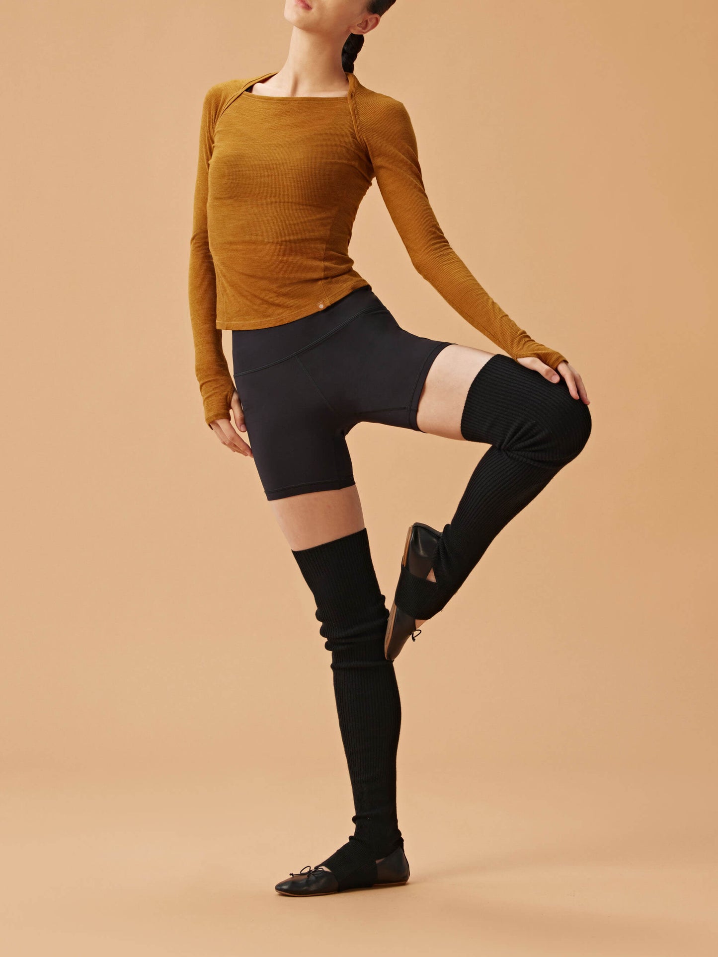 woman in golden brown wool top and black biker shorts and leg warmers.