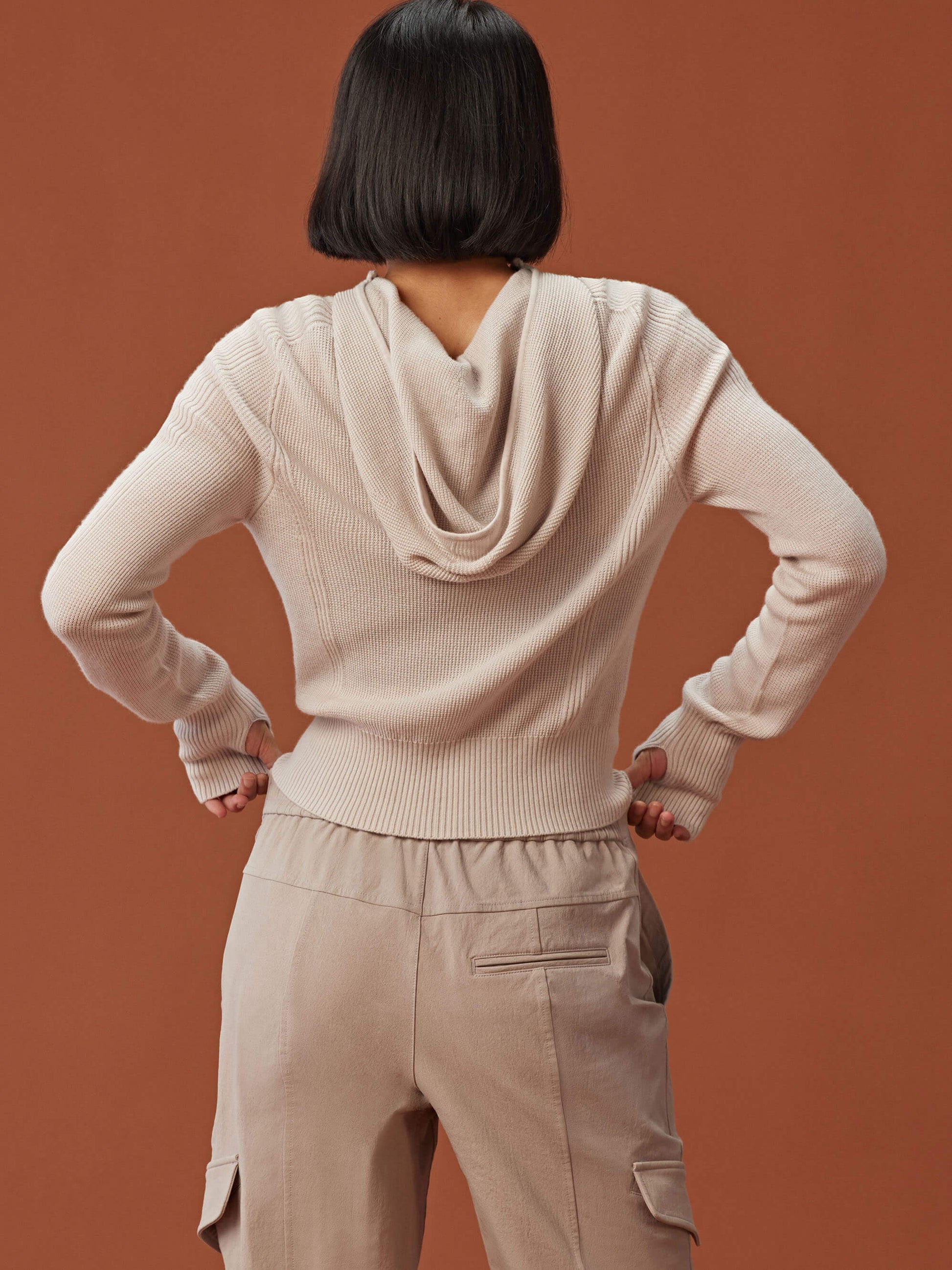 back of woman in beige knitted hoodie