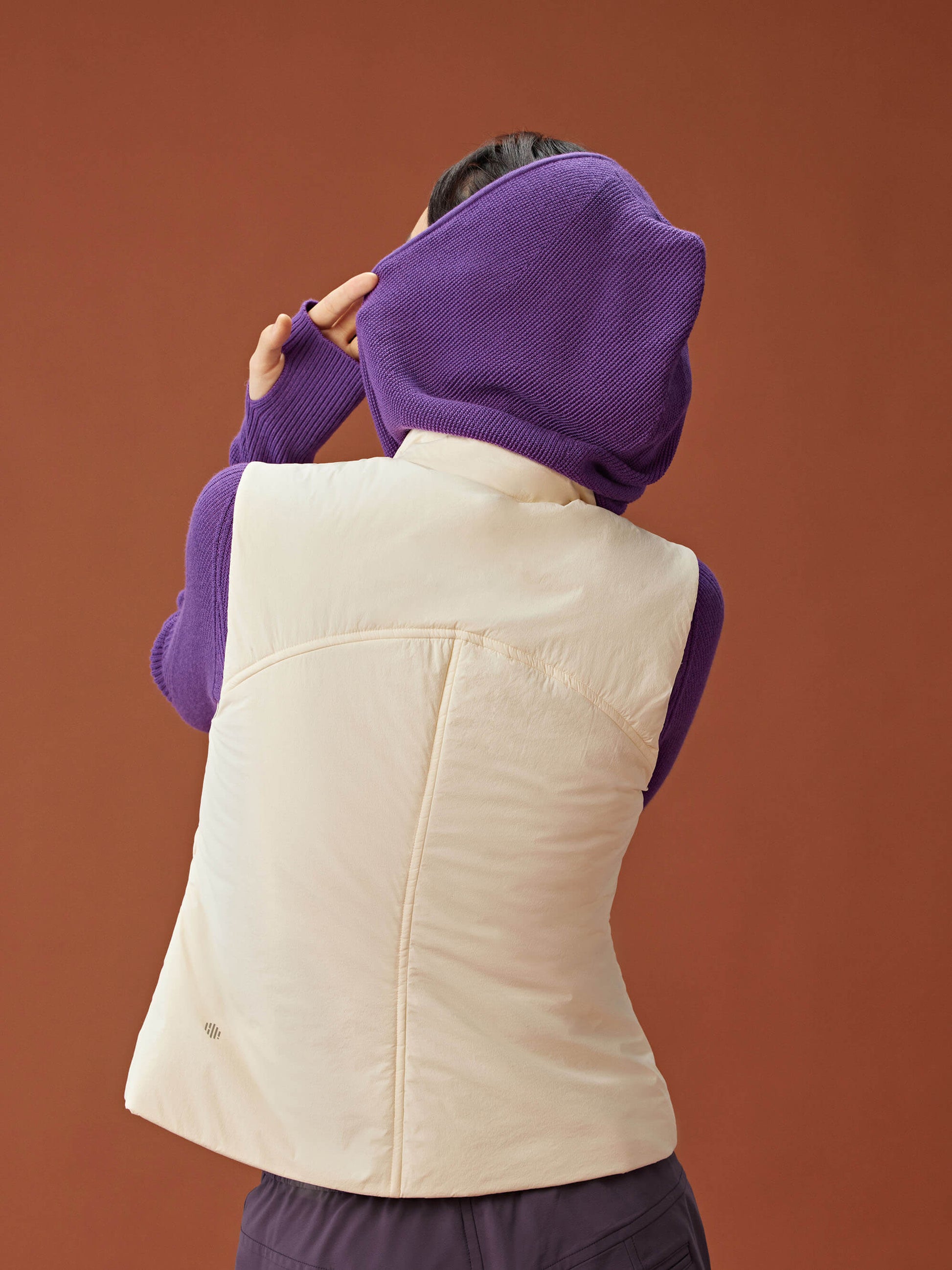 back of woman in purple knitted hoodie and white vest