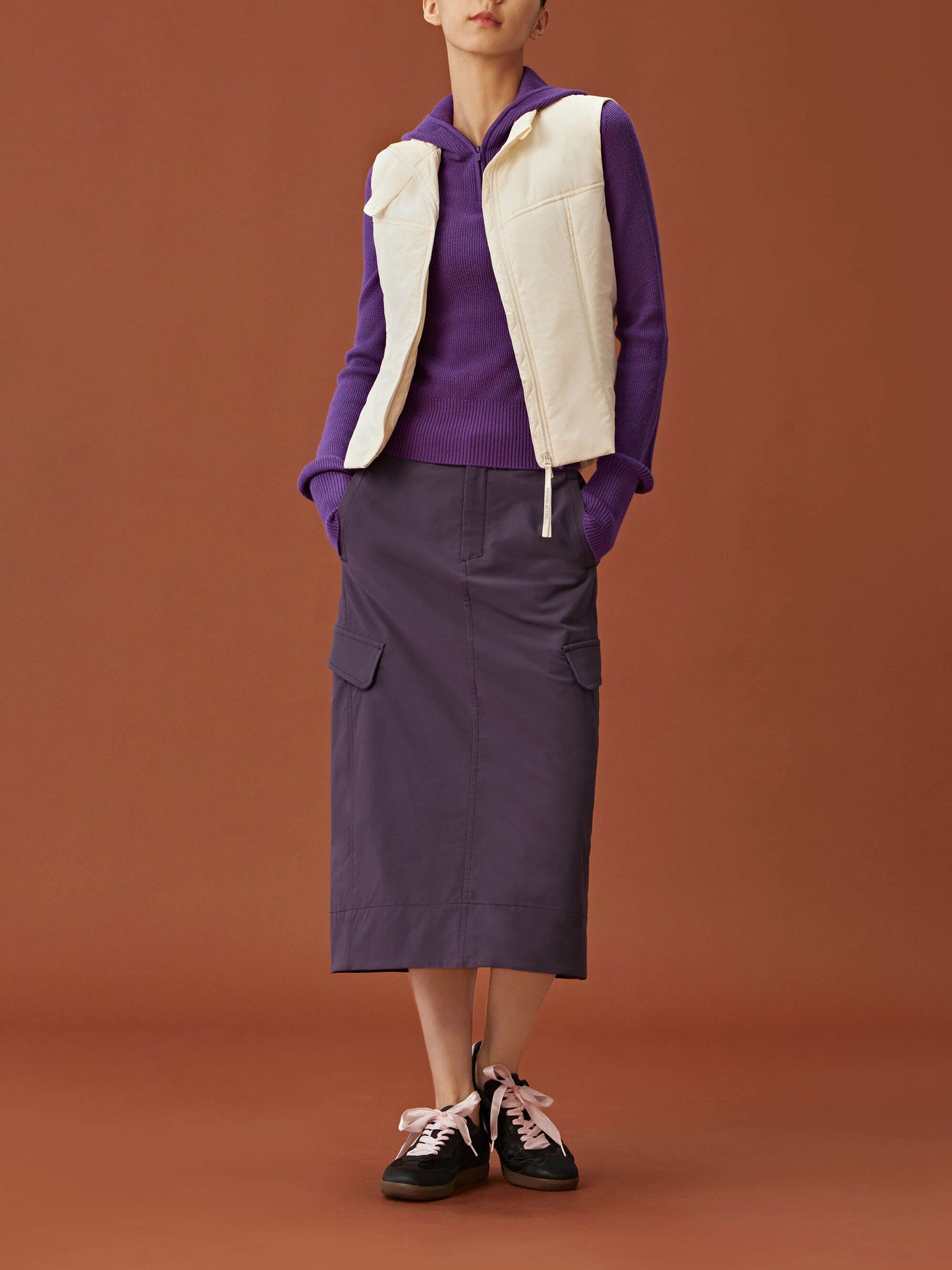 woman in purple hoodie, white vest and purple skirt