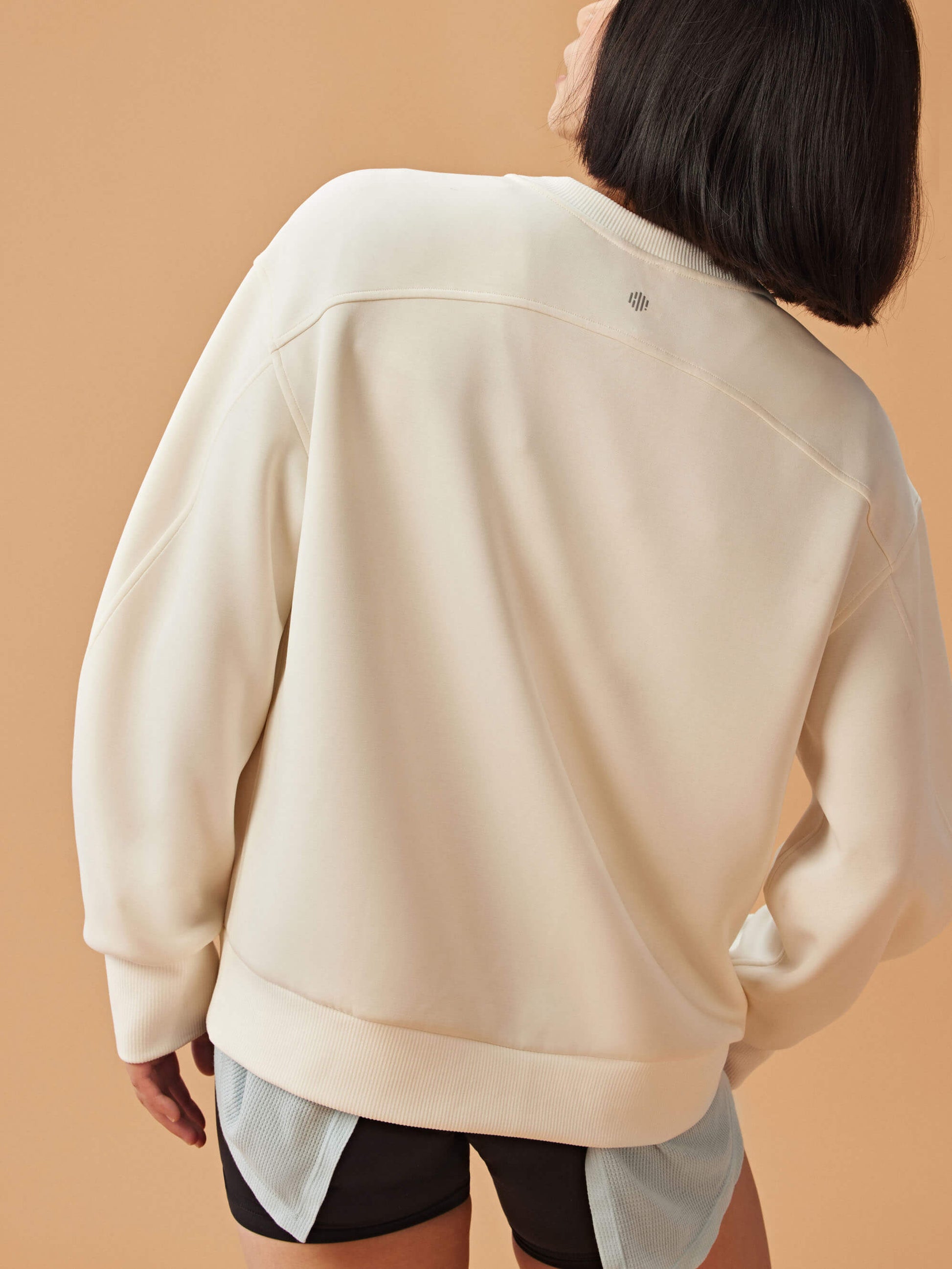 Back view of woman wearing white sweatshirt and black shorts