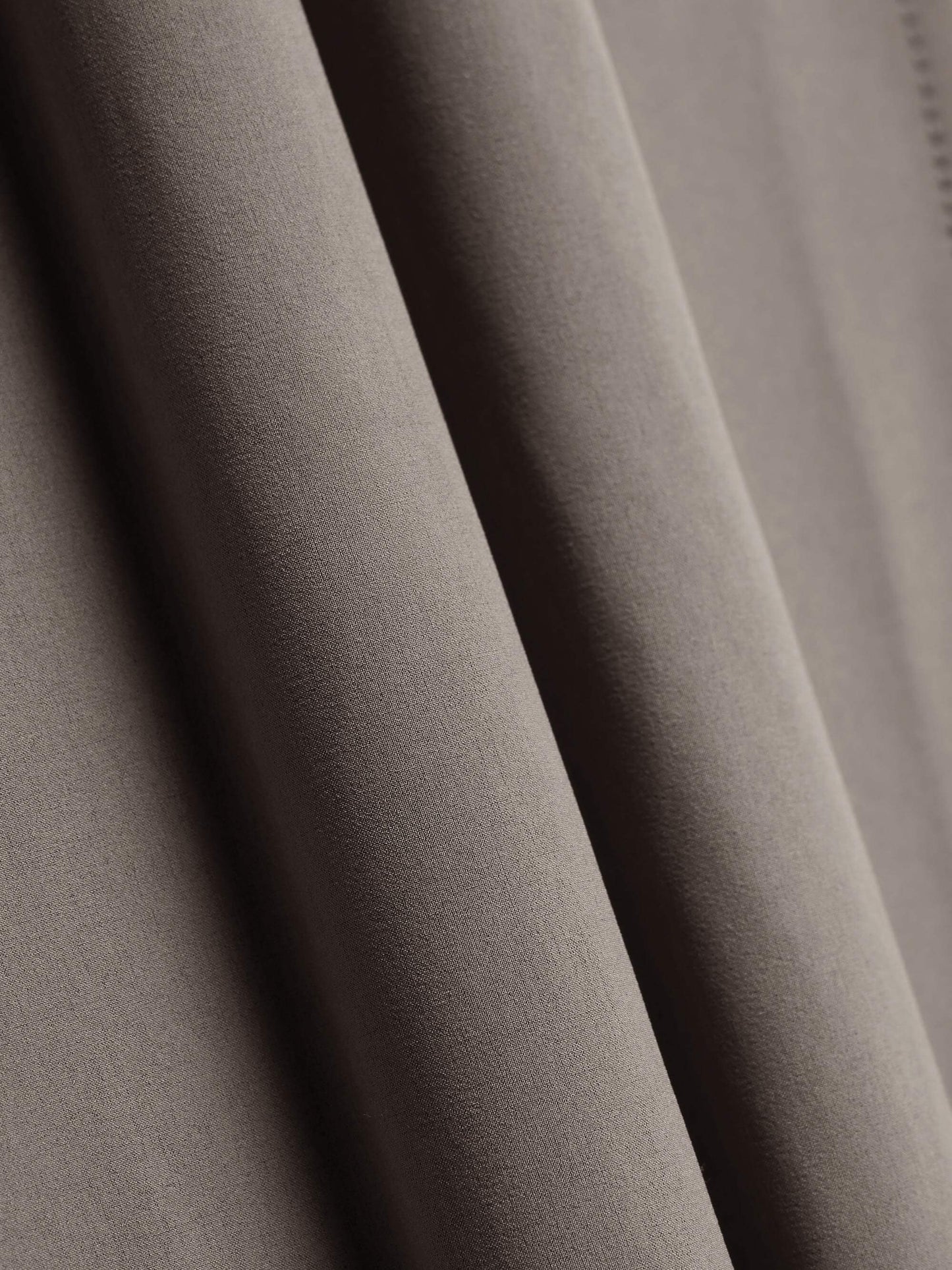 Close-up of beige fabric, showing smooth, flowing texture and soft folds.