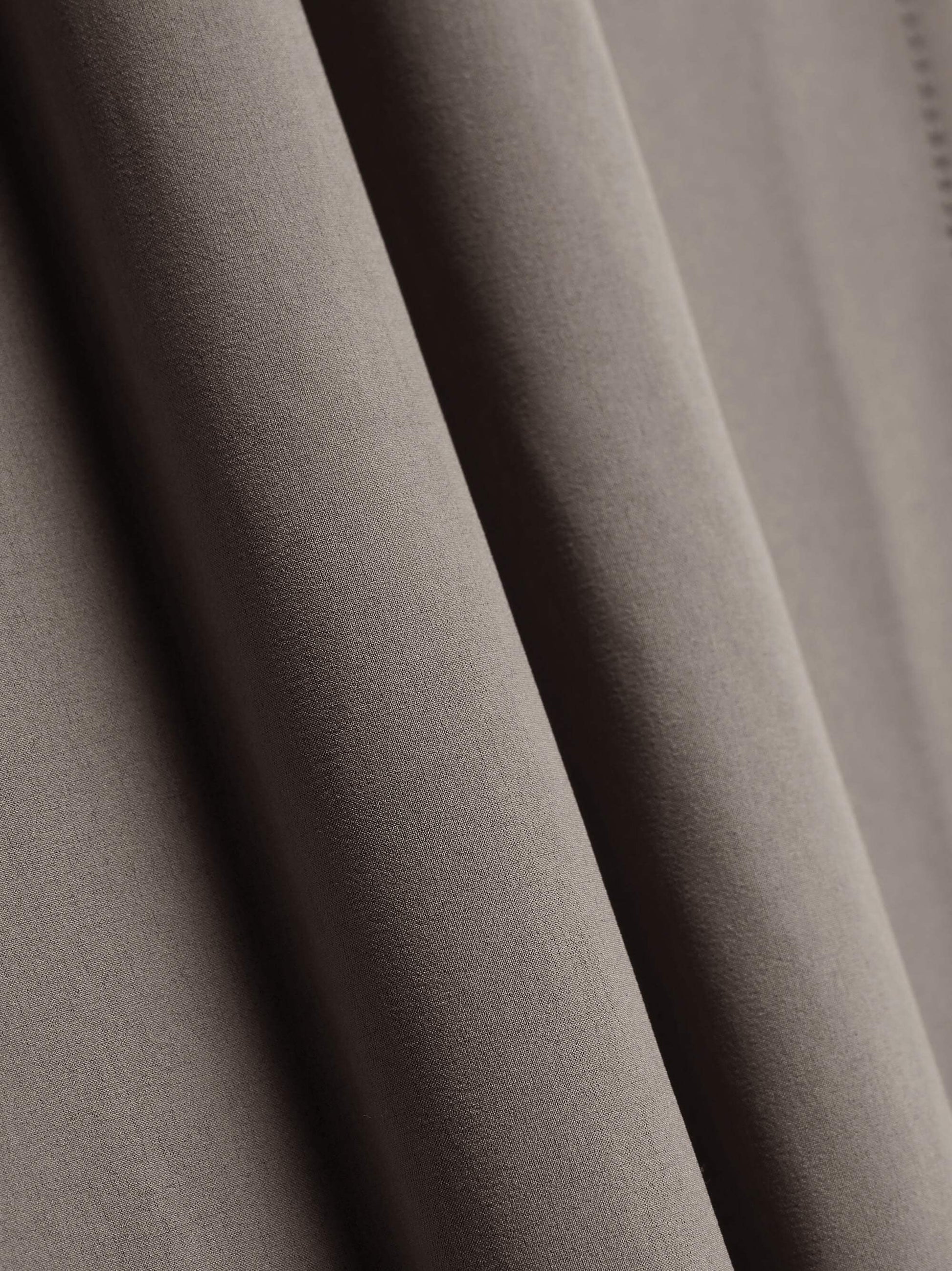 Close-up of beige fabric, showing smooth, flowing texture and soft folds.