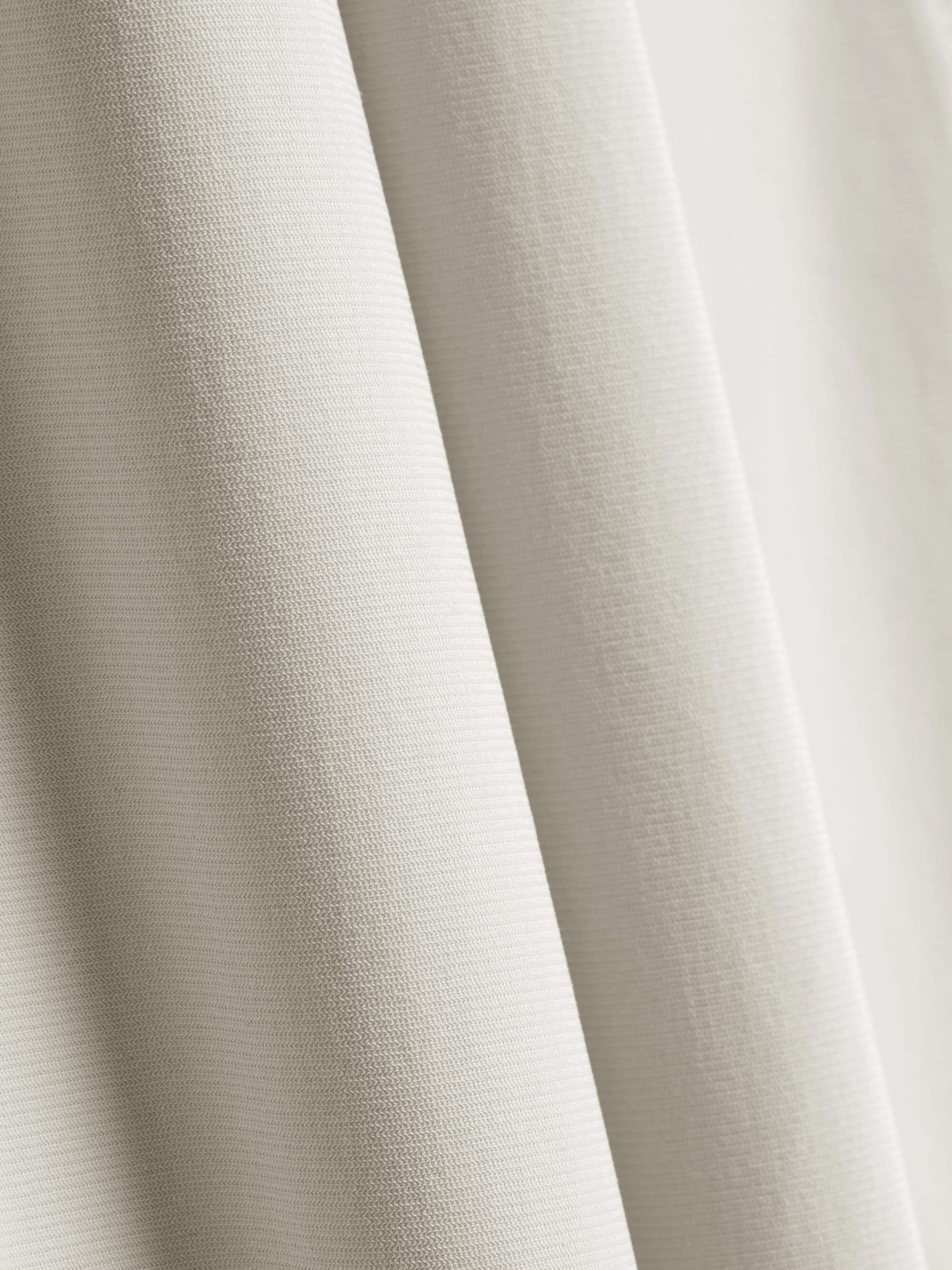 Close-up of the fabric used for white straight-leg pants, showcasing its fine texture and quality. 