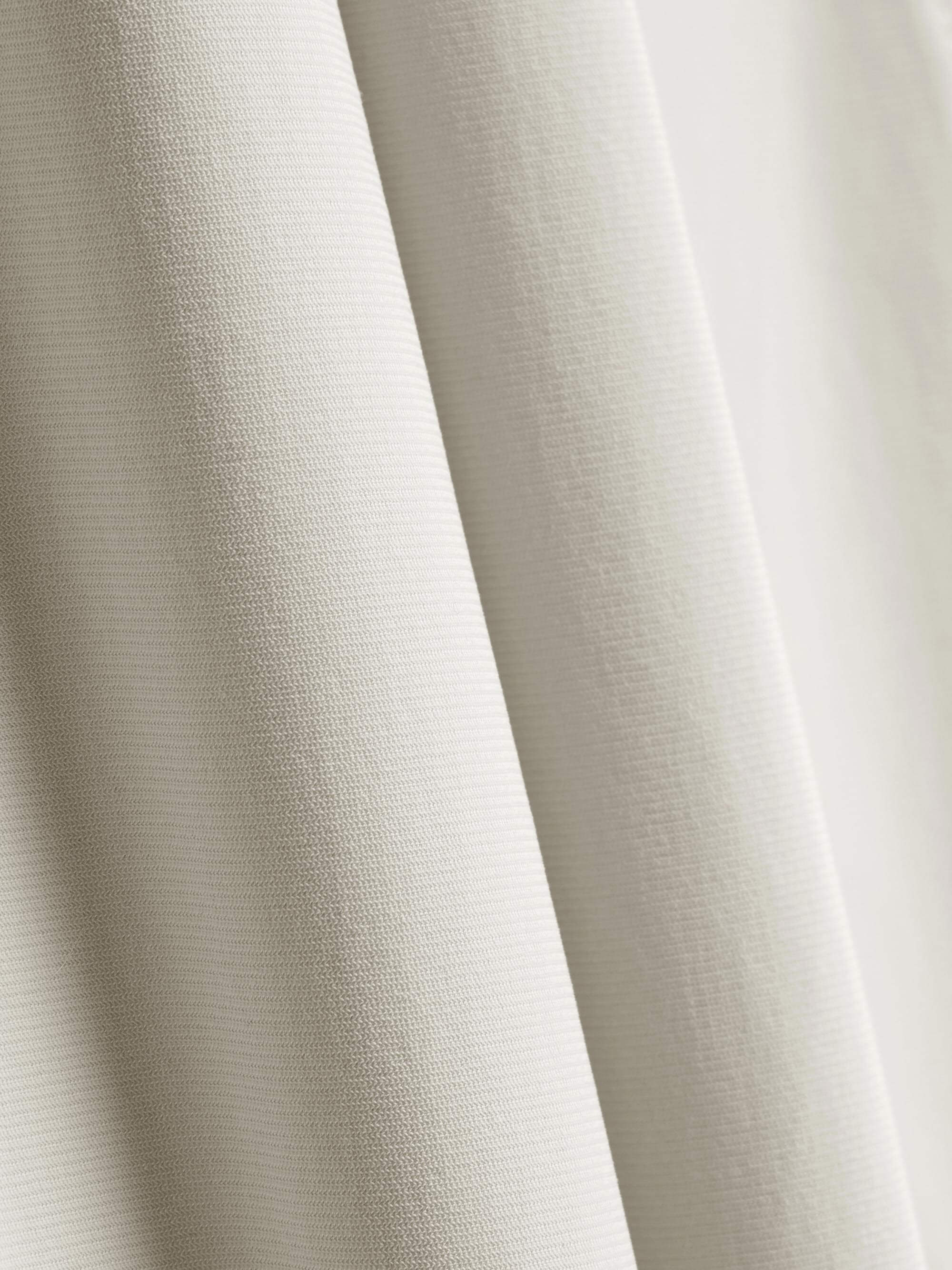 Close-up of the fabric used for white straight-leg pants, showcasing its fine texture and quality. 