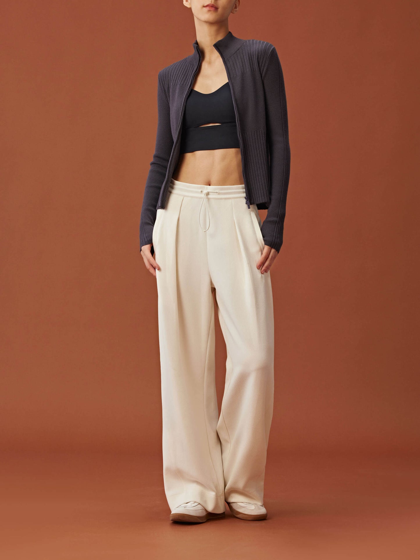 woman in black sports bra, purple cardigan and white wide leg pants