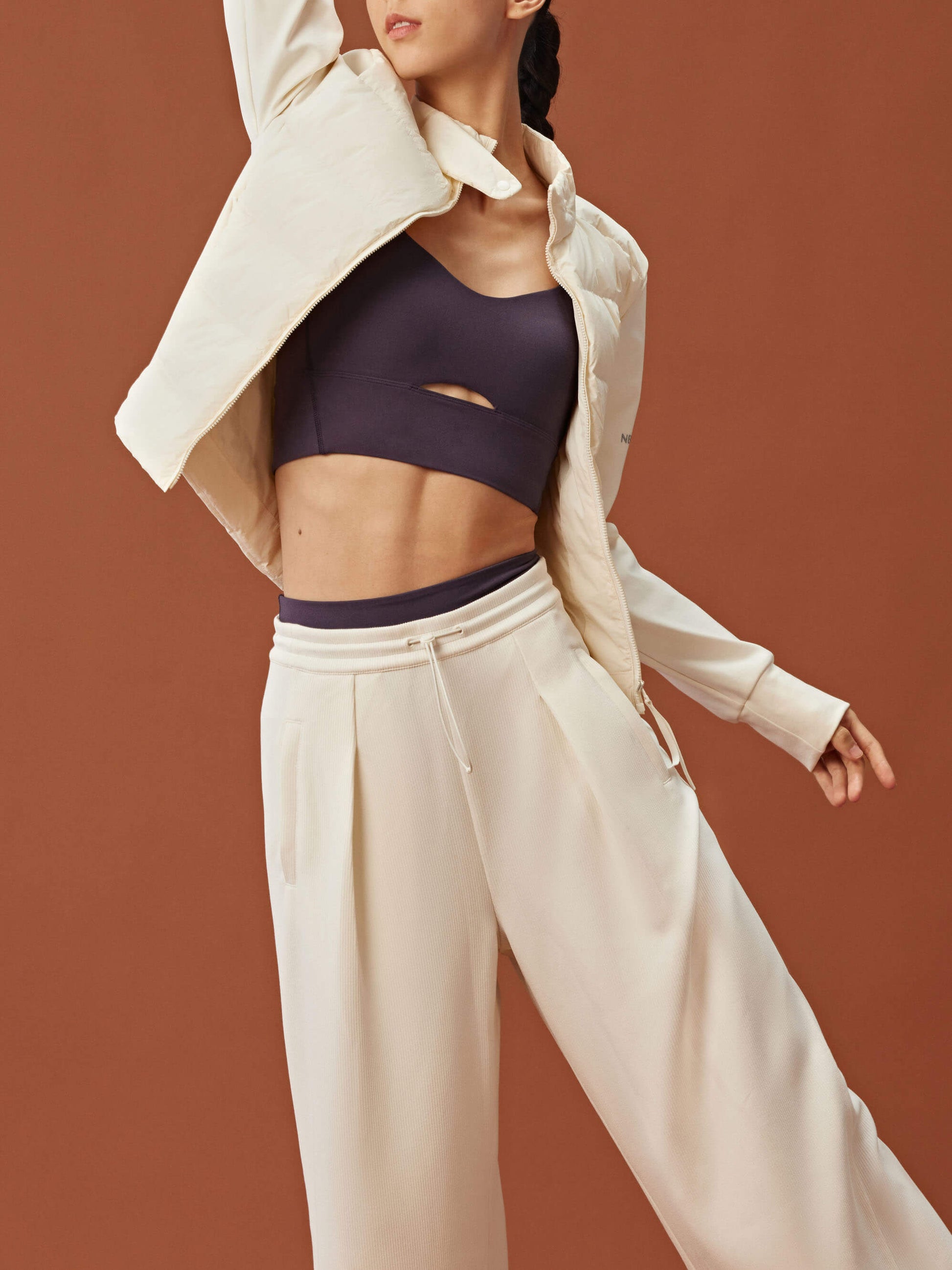 woman in dark purple sports bra, white jacket and white wide leg pants