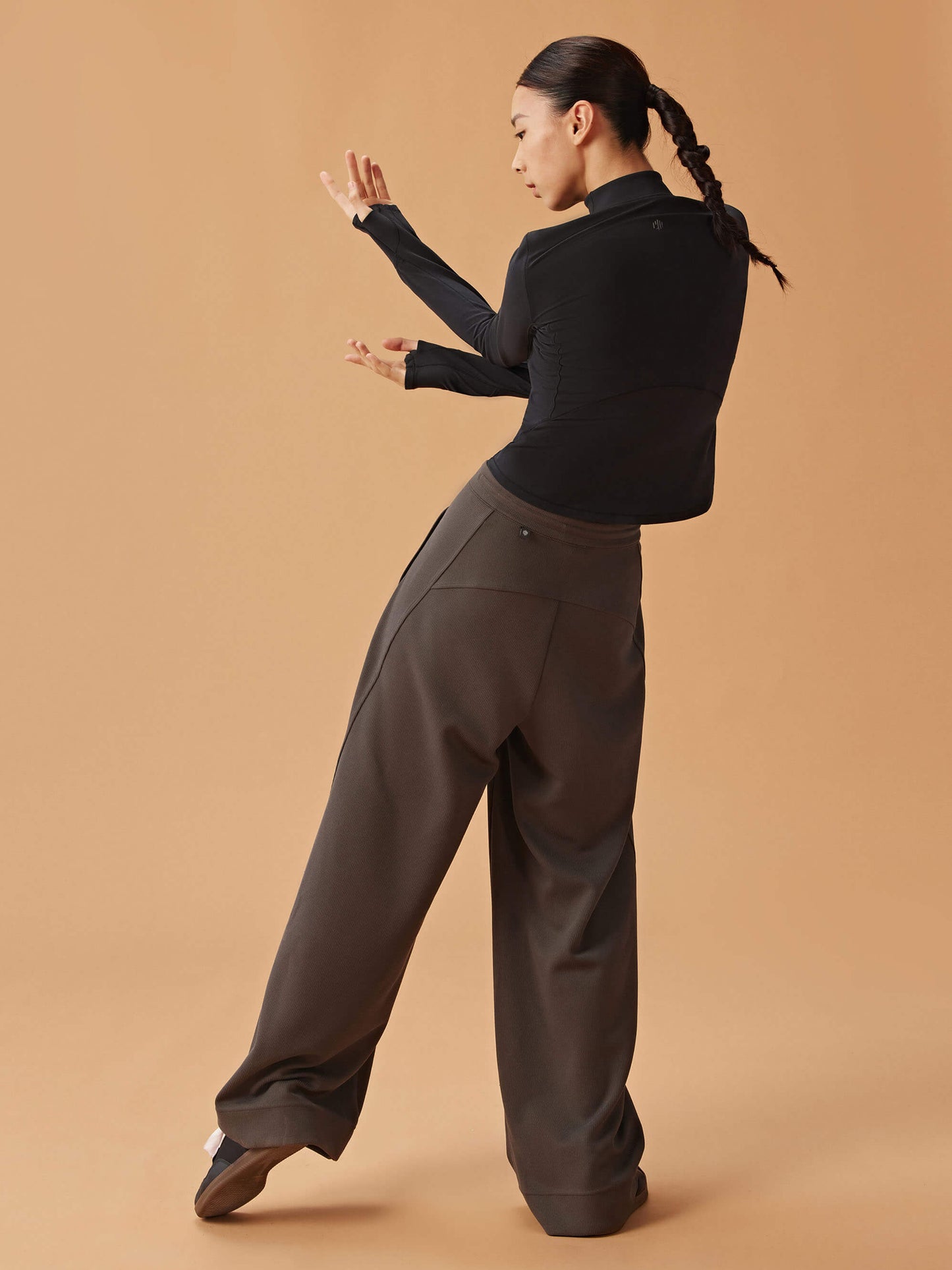 back of woman in black long sleeve top and dark gray wide leg pants