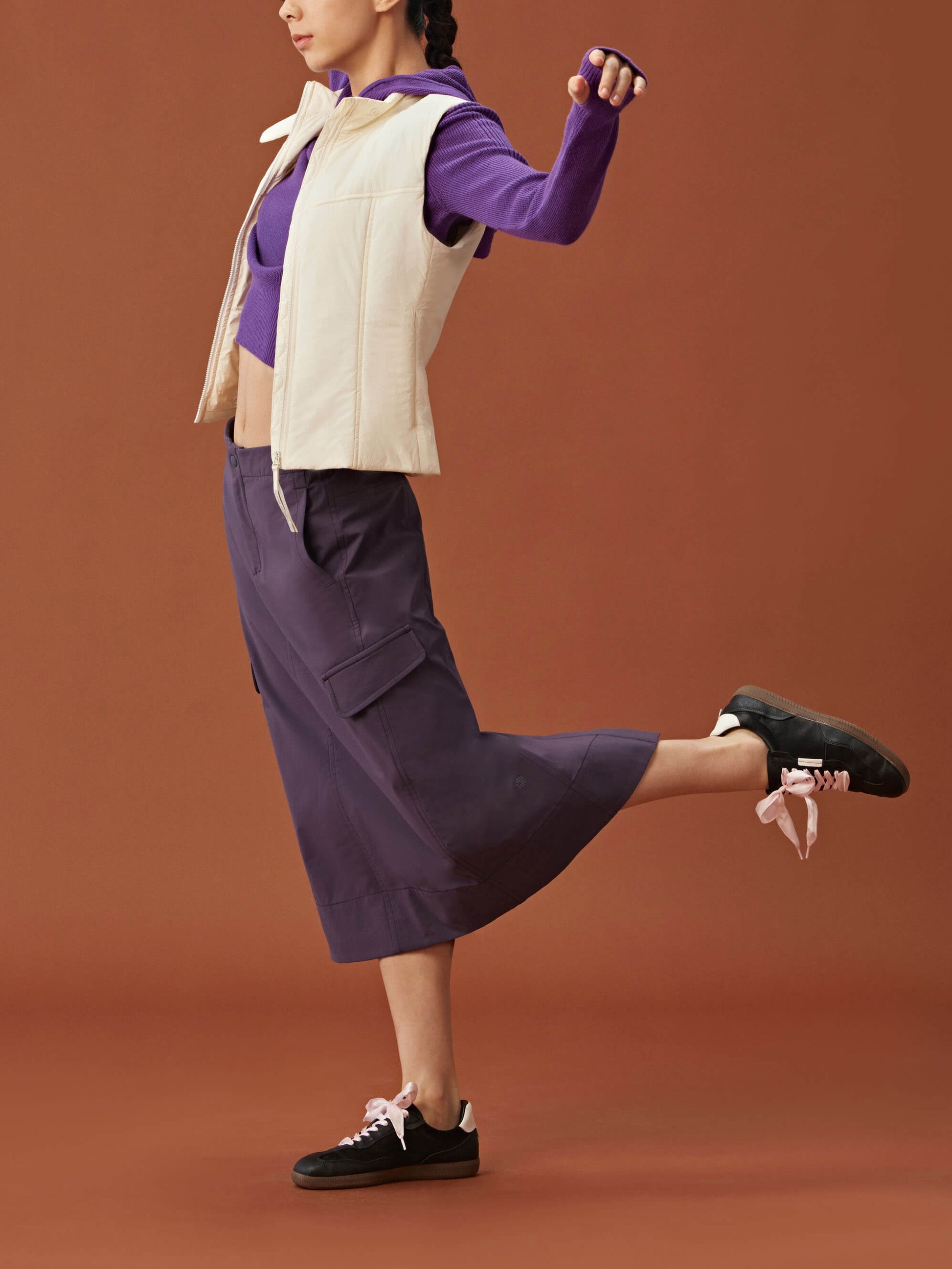 woman in purple hoodie, white vest and purple midi skirt.