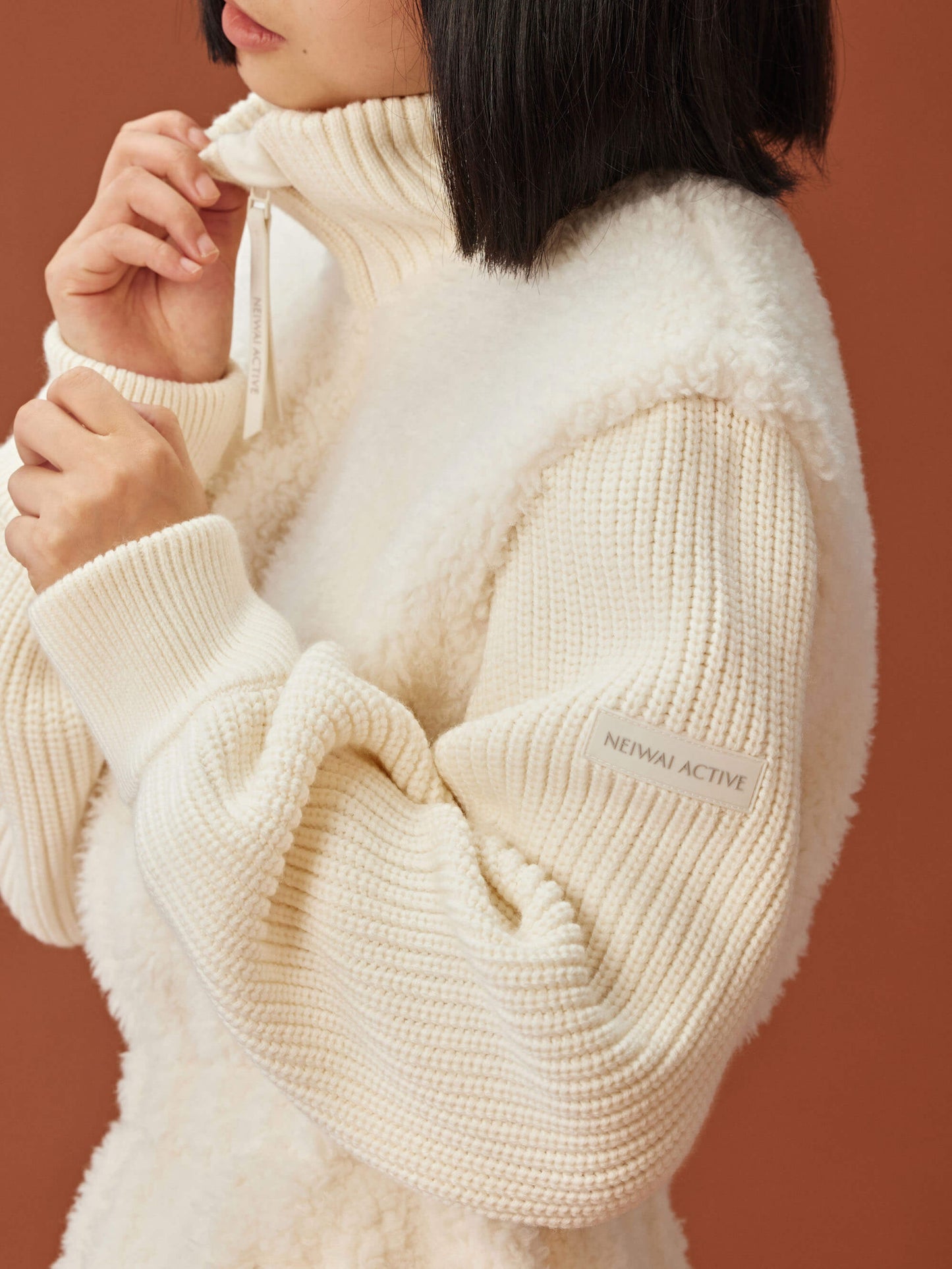 close up of woman in white fleece coat with gathered waist and knitted sleeves