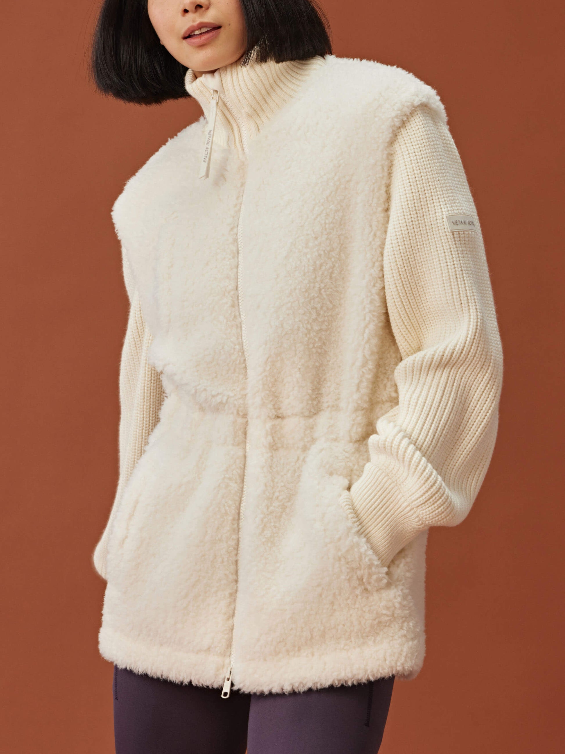 woman in white fleece coat with gathered waist and knitted sleeves